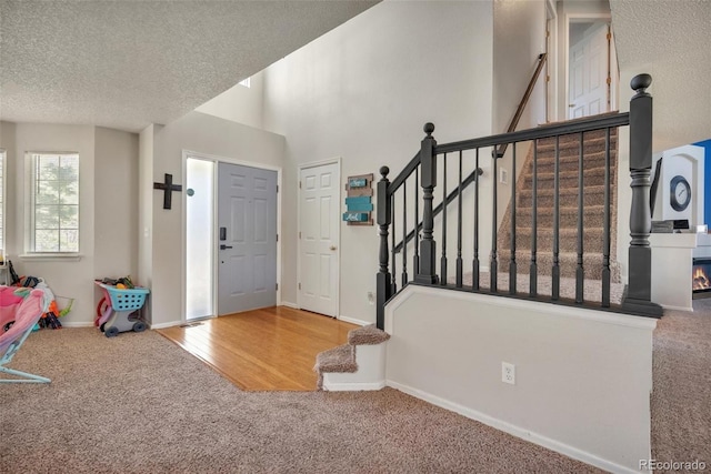 foyer featuring stairway, baseboards, carpet flooring, and a textured ceiling