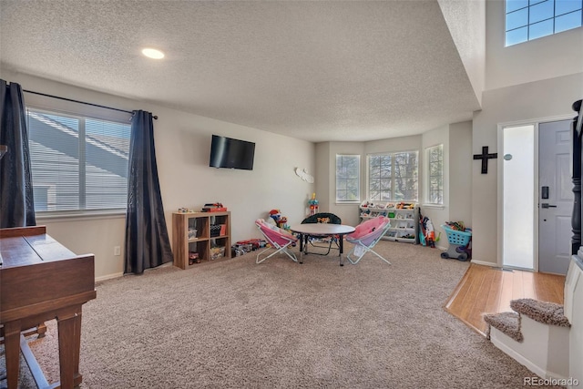 recreation room with carpet floors, a textured ceiling, and a healthy amount of sunlight