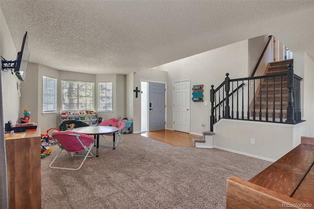 recreation room featuring baseboards, a textured ceiling, and carpet