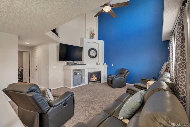 carpeted living room featuring a ceiling fan, baseboards, a textured ceiling, and a fireplace