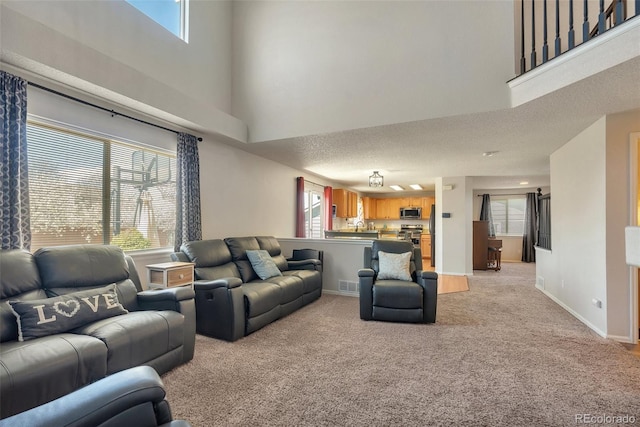 living area with a high ceiling, baseboards, light carpet, and visible vents