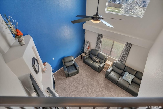 living area with carpet floors, a towering ceiling, baseboards, and ceiling fan