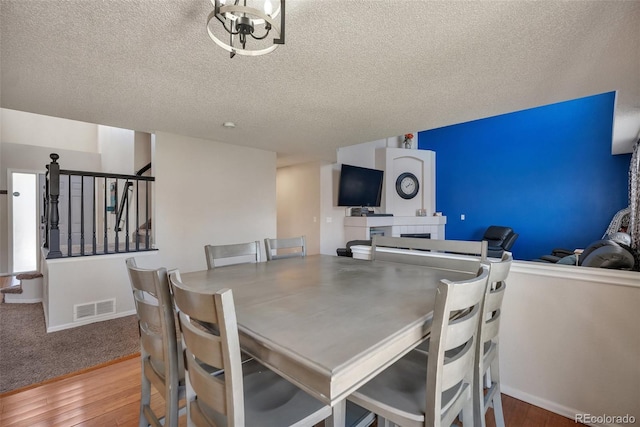 dining space featuring a textured ceiling, stairway, visible vents, and hardwood / wood-style flooring