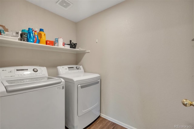 laundry room with laundry area, wood finished floors, visible vents, washing machine and dryer, and baseboards