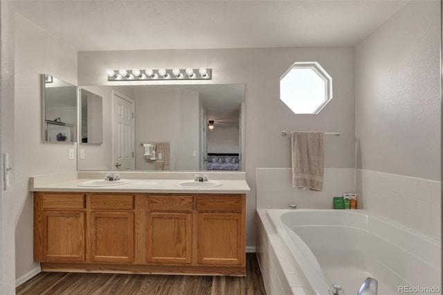 bathroom featuring a garden tub, wood finished floors, a sink, and double vanity
