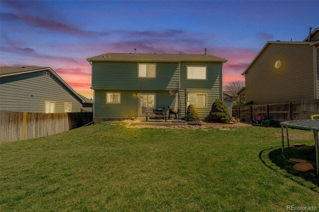 back of property at dusk featuring a fenced backyard, a yard, and a patio