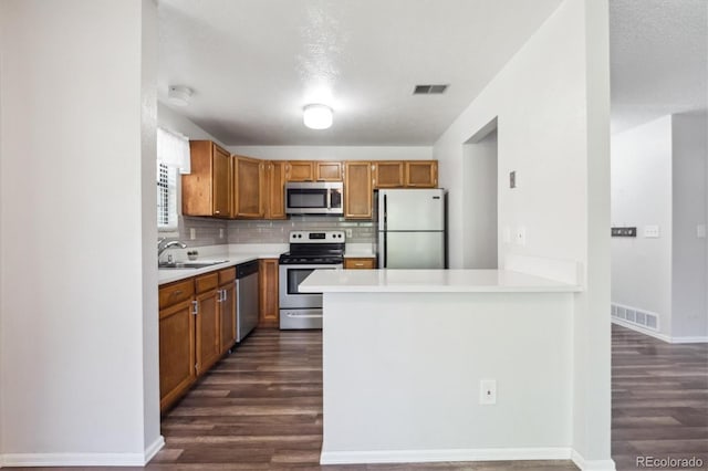 10950 W Florida Ave Unit 314, Lakewood, CO 80232 - kitchen with stainless steel appliances, dark wood-type flooring, light countertops, decorative backsplash, and a peninsula