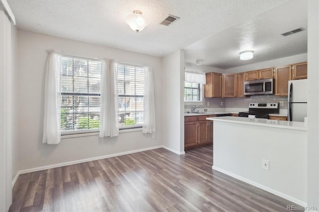 10950 W Florida Ave Unit 314, Lakewood, CO 80232 - kitchen featuring appliances with stainless steel finishes, wood finished floors, light countertops, decorative backsplash, and a textured ceiling