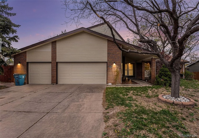 view of front of home featuring brick siding, a garage, fence, and driveway