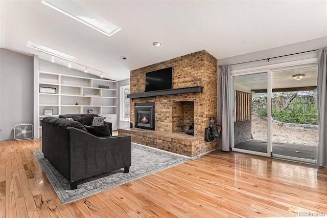 living area featuring wood-type flooring, track lighting, a healthy amount of sunlight, and a fireplace