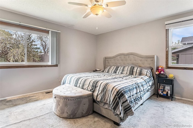carpeted bedroom featuring baseboards, multiple windows, a ceiling fan, and visible vents