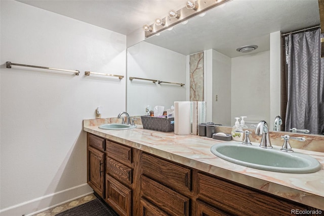 full bathroom with baseboards, a sink, and double vanity