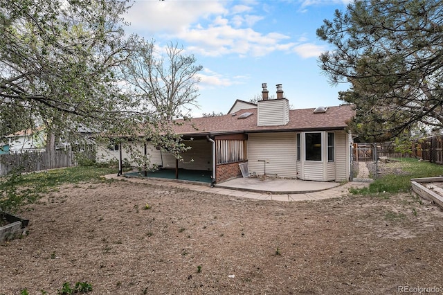 back of property with a patio, a fenced backyard, a chimney, and a shingled roof
