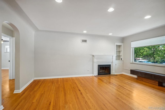 unfurnished living room featuring ceiling fan, a fireplace, and light hardwood / wood-style floors