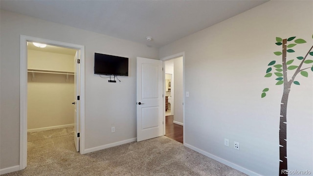 unfurnished bedroom with a walk in closet, light colored carpet, and a closet