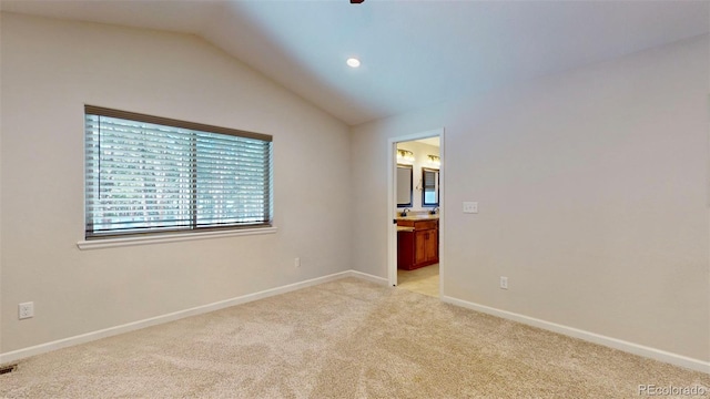 spare room featuring light colored carpet and lofted ceiling