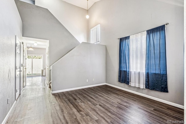 unfurnished living room with hardwood / wood-style flooring and a towering ceiling