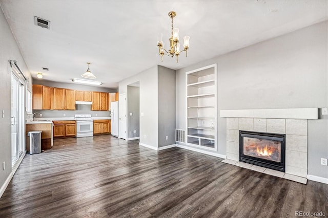 unfurnished living room featuring dark hardwood / wood-style flooring, sink, built in shelves, and a tile fireplace