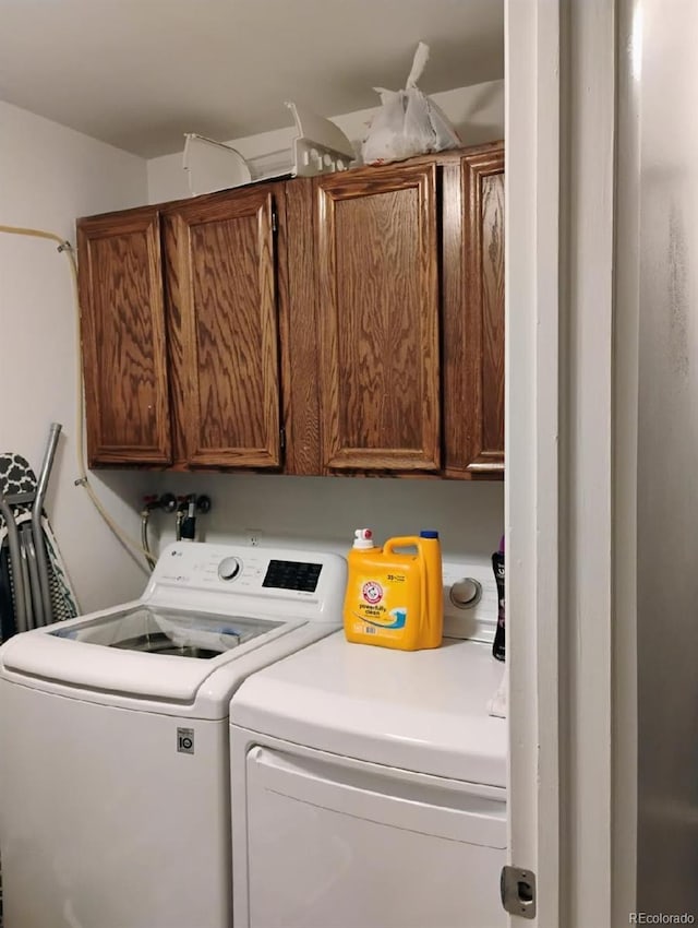 clothes washing area featuring independent washer and dryer and cabinets