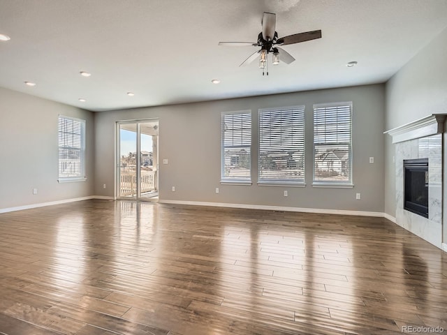 unfurnished living room featuring a fireplace, recessed lighting, ceiling fan, wood finished floors, and baseboards