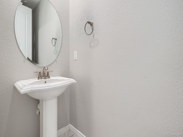 bathroom with a textured wall and baseboards