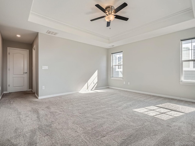 unfurnished room featuring a tray ceiling, carpet, visible vents, and baseboards