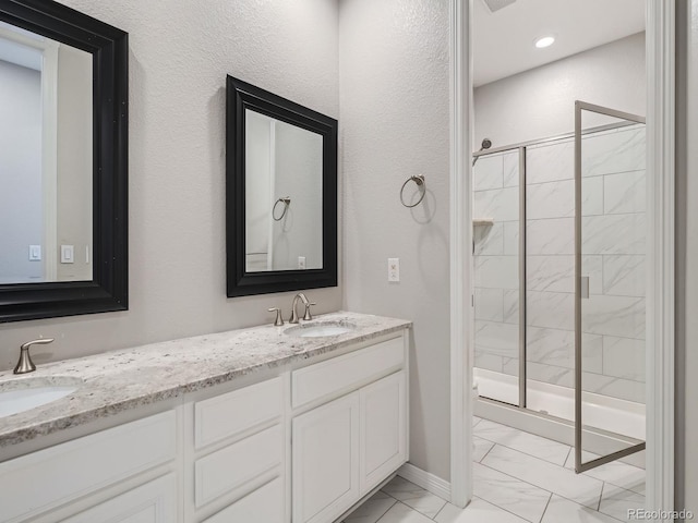 bathroom featuring a stall shower, marble finish floor, and a sink