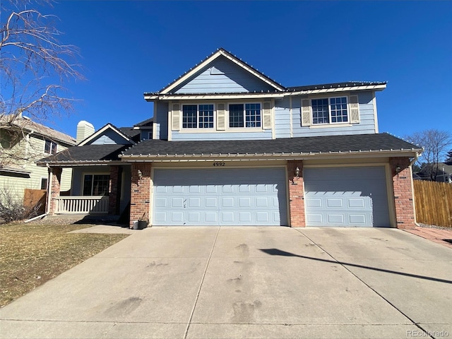 traditional home featuring an attached garage, covered porch, brick siding, fence, and concrete driveway