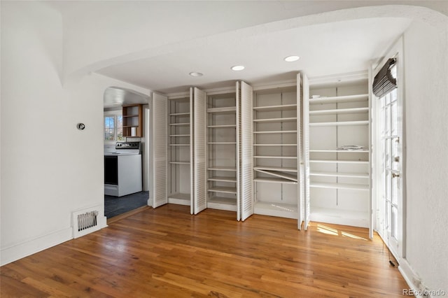 interior space with wood finished floors, recessed lighting, visible vents, and arched walkways