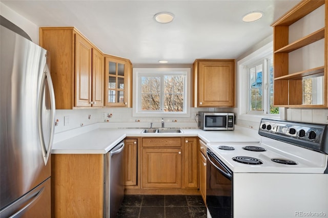 kitchen with a sink, open shelves, stainless steel appliances, light countertops, and glass insert cabinets