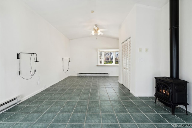 empty room with dark tile patterned floors, a ceiling fan, baseboard heating, a wood stove, and vaulted ceiling