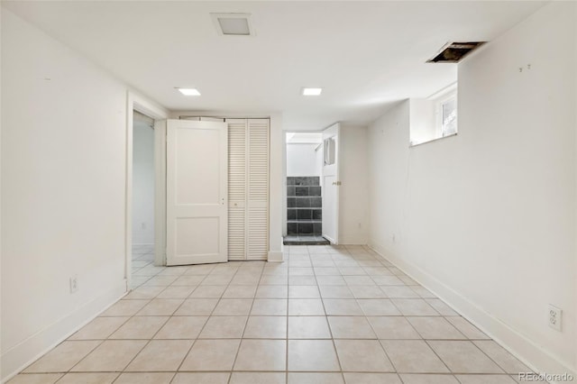 basement with baseboards, light tile patterned flooring, and stairs