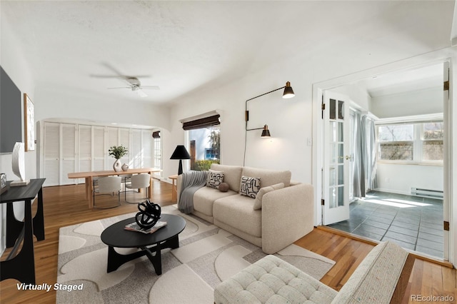 living room featuring ceiling fan, a baseboard heating unit, and wood finished floors