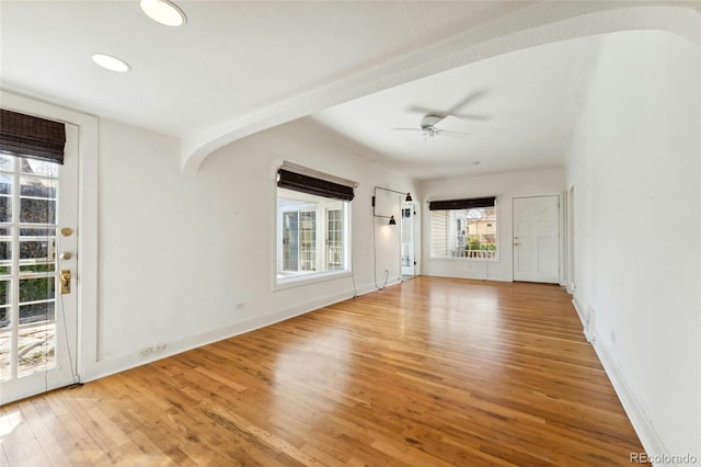 spare room with recessed lighting, arched walkways, light wood-style floors, baseboards, and ceiling fan