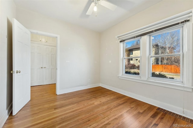 empty room with a ceiling fan, light wood-type flooring, and baseboards