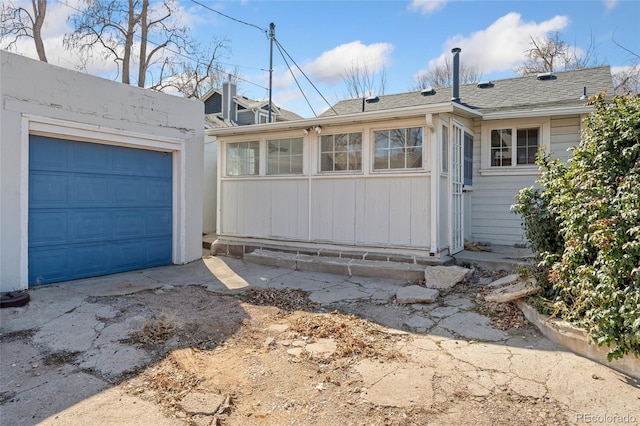 exterior space with a garage, driveway, and a shingled roof