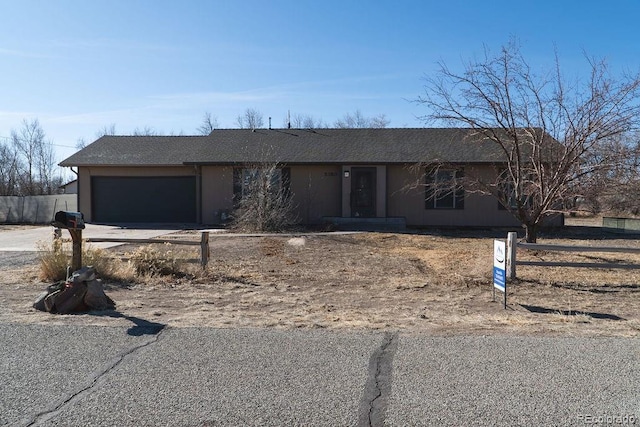 view of front facade featuring concrete driveway, an attached garage, and fence