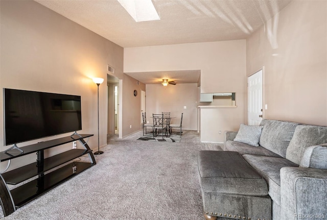 carpeted living room with a towering ceiling, a textured ceiling, and a skylight