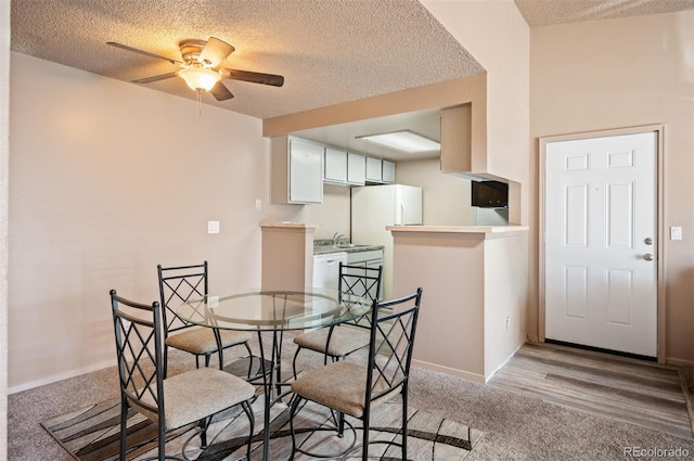 dining space with ceiling fan, a textured ceiling, and light wood-type flooring