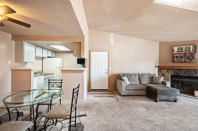 carpeted living room featuring ceiling fan, a fireplace, and a textured ceiling