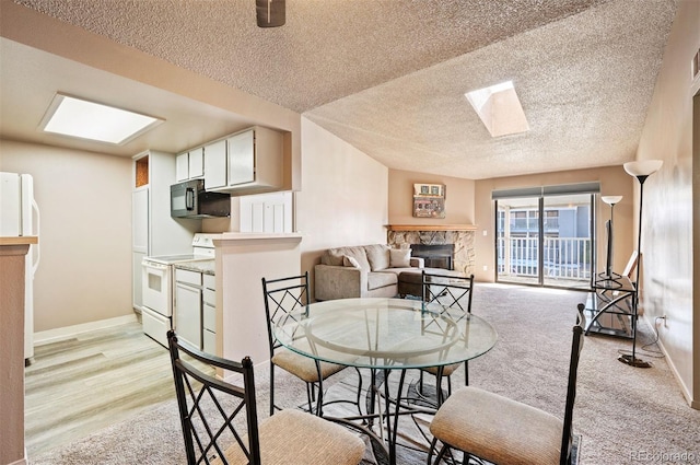 dining space featuring a textured ceiling, a skylight, a fireplace, and light hardwood / wood-style flooring