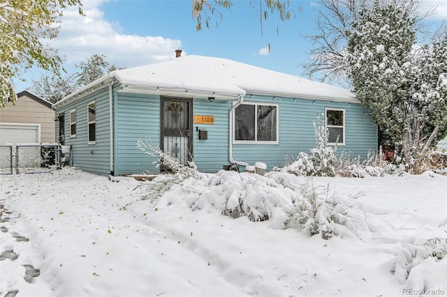 snow covered back of property with a garage