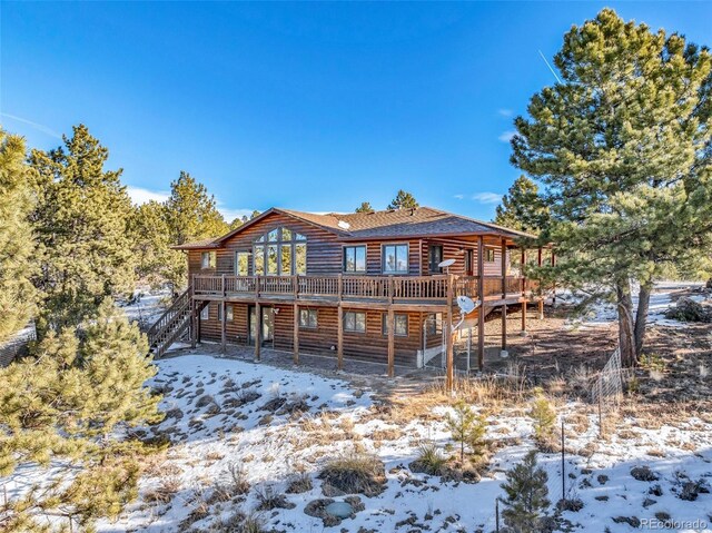 820 Schulze Ranch Rd, Westcliffe, CO 81252 - snow covered rear of property with log veneer siding, a deck, stairs, and roof with shingles
