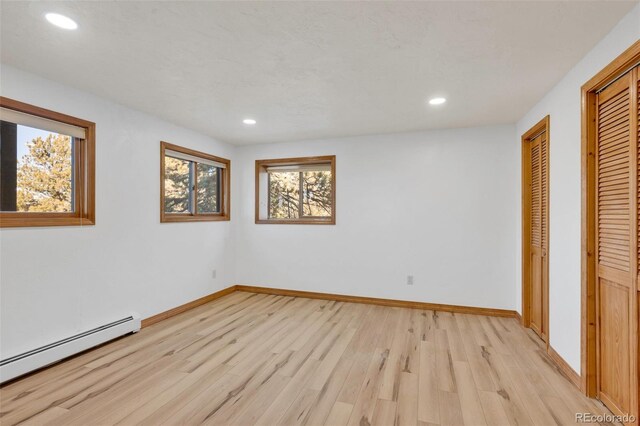 820 Schulze Ranch Rd, Westcliffe, CO 81252 - unfurnished bedroom featuring baseboard heating, light wood finished floors, recessed lighting, baseboards, and two closets