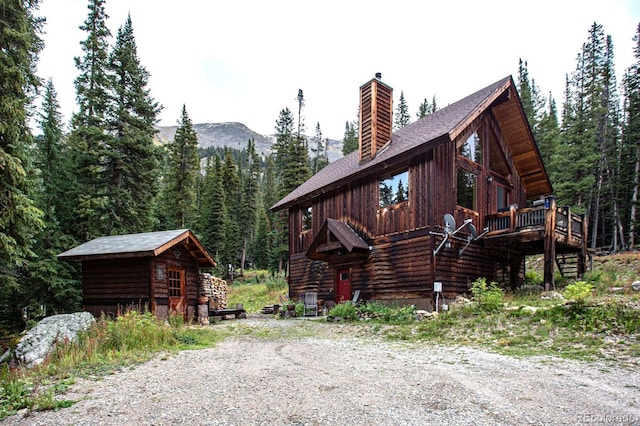 10 Bullion Mine Rd, Keystone, CO 80435 - view of front of property featuring a chimney, a wooded view, an outbuilding, stairway, and a deck with mountain view