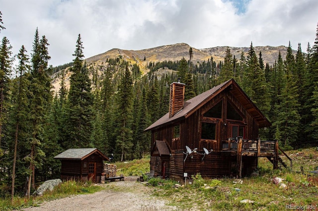 10 Bullion Mine Rd, Keystone, CO 80435 - view of front of property with a wooded view, a deck with mountain view, a chimney, an outbuilding, and stairs