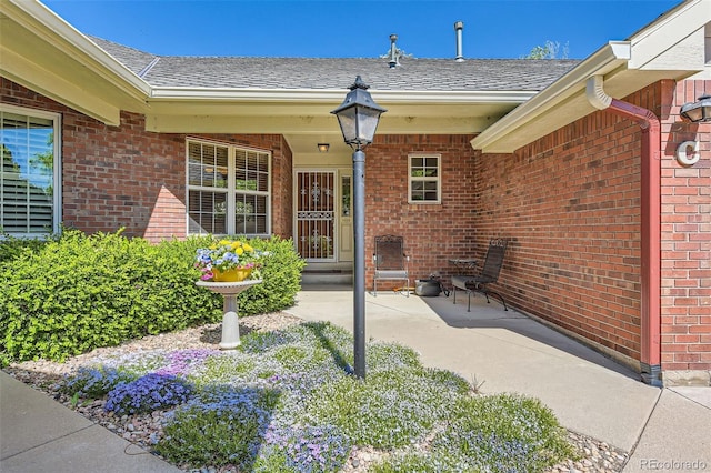 2700 W Riverwalk Cir Unit C, Littleton, CO 80123 - view of exterior entry with brick siding, a shingled roof, and a patio