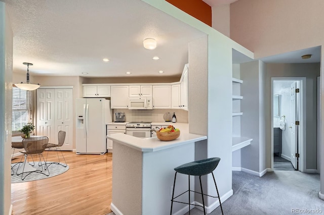 2700 W Riverwalk Cir Unit C, Littleton, CO 80123 - kitchen featuring white appliances, a peninsula, white cabinets, light countertops, and tasteful backsplash