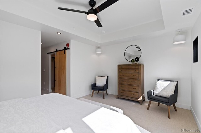 bedroom featuring ceiling fan, light colored carpet, a tray ceiling, and a barn door