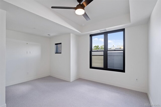 carpeted empty room featuring ceiling fan and a tray ceiling